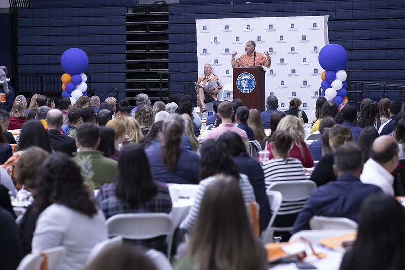 Standing behind a podium while facing a crowd, President Virjee thanks everyone for their hard work at CSUF.