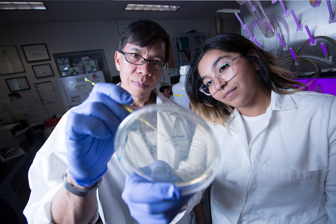 a man and a woman in lab coats looking at a petri dish
