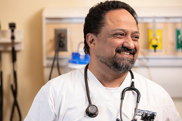 Nursing Student John Jadia in white scrubs with a stethoscope around his neck