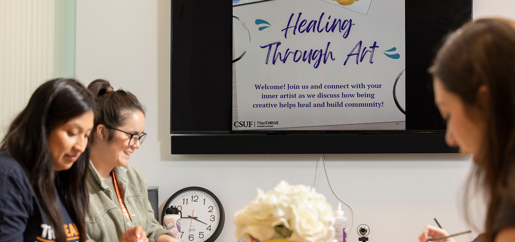 People engaging in an art activity under a screen titled "Healing Through Art."
