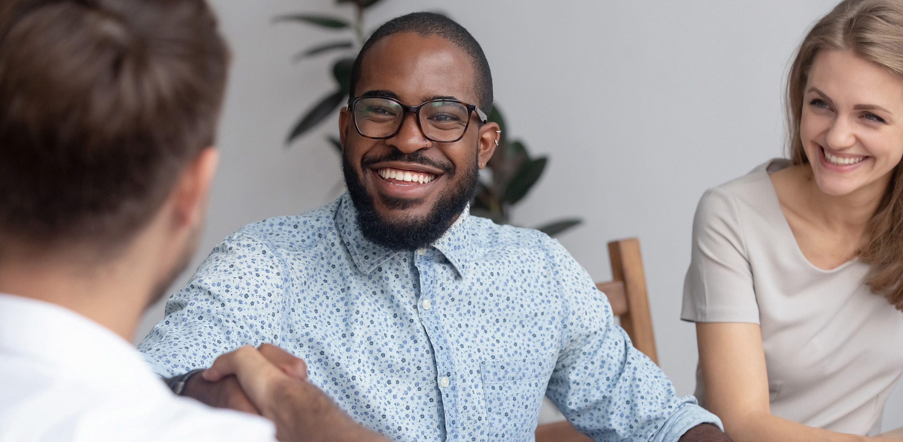 three people sitting together at a table, two of them are shaking hands