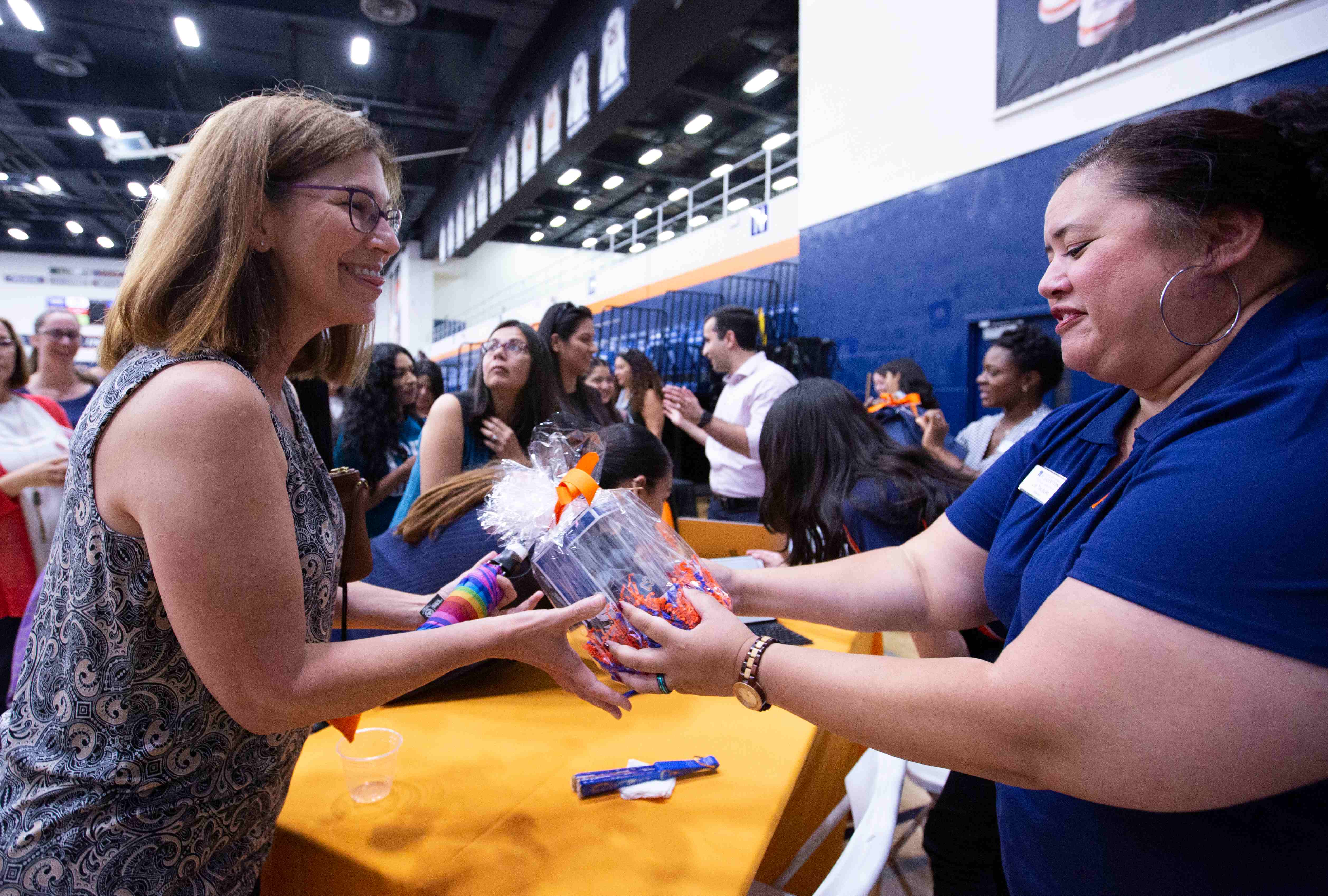 a woman handing another woman a gift at an event