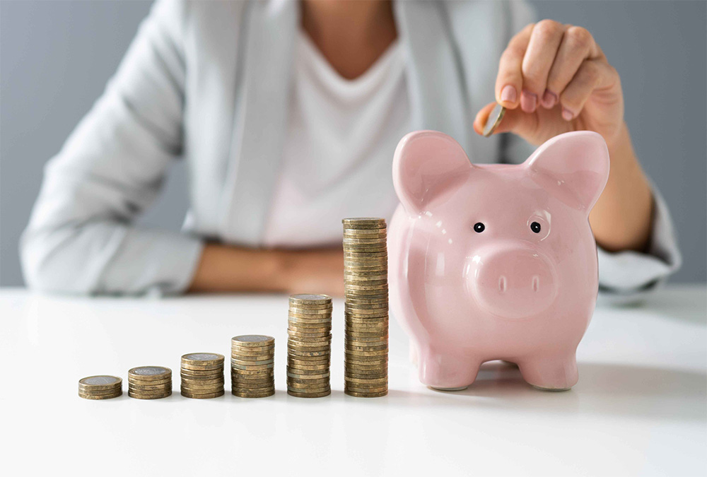 person putting coins in a piggy bank