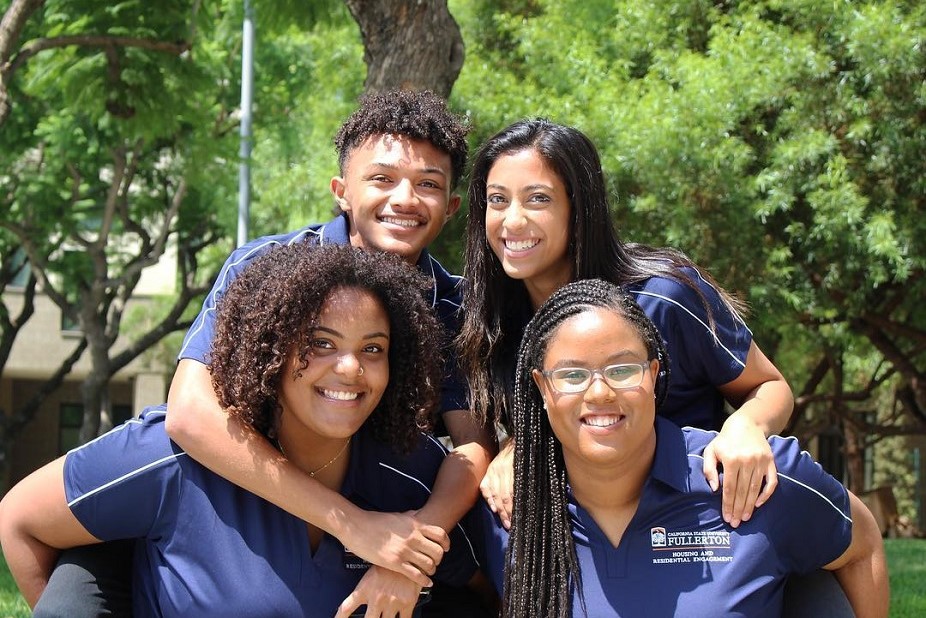 3 female and 1 male CSUF student employees smiling together for picture