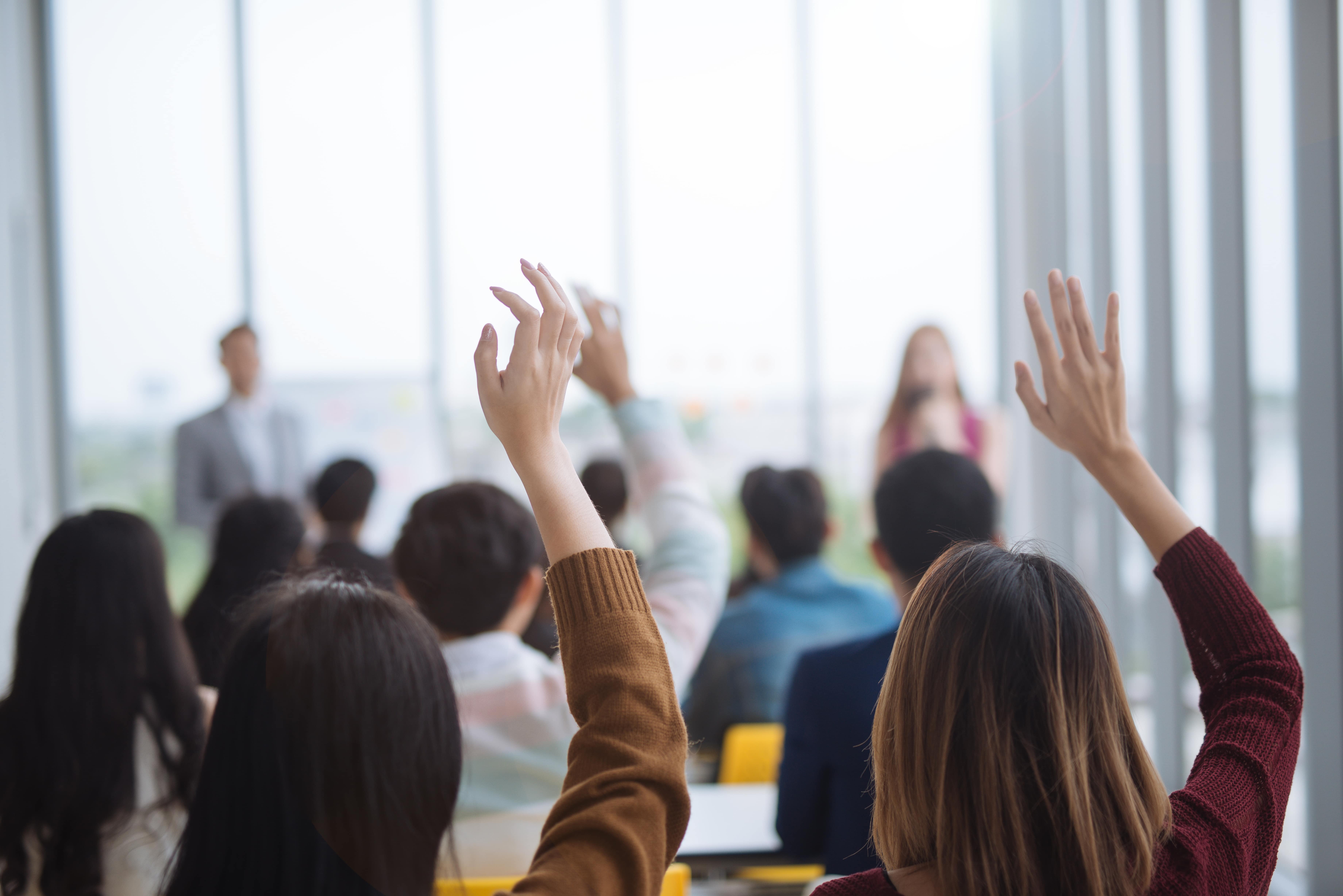 Students raising their hands in a classroom setting