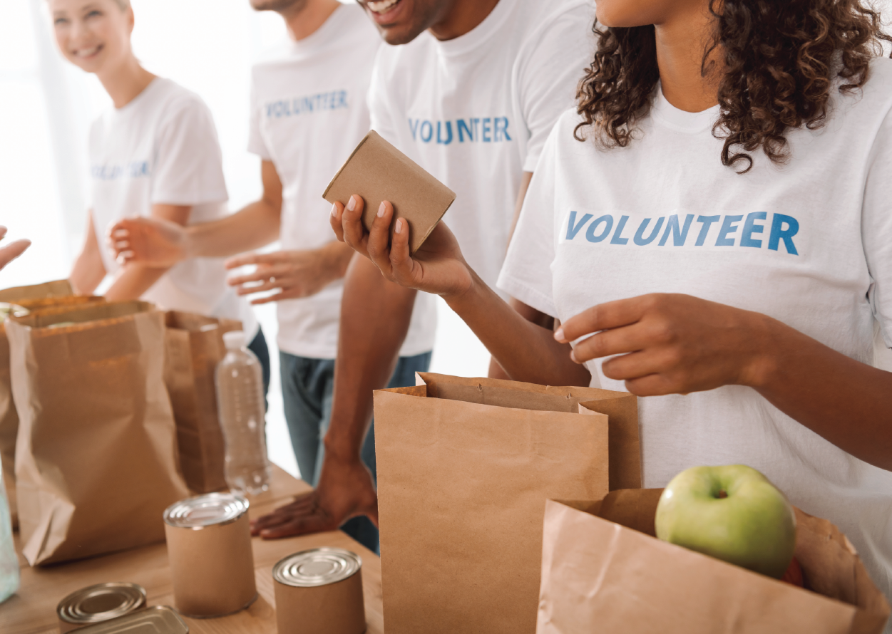 4 volunteers putting together food in brown bags