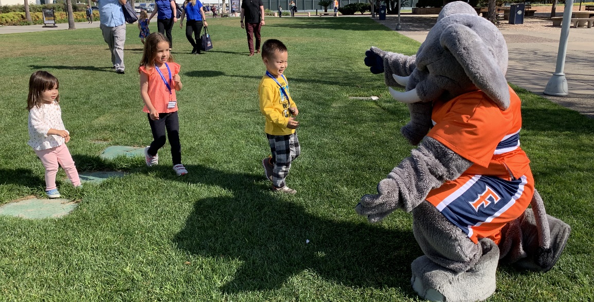 Tuffy playing w/ 3 children on the lawn at bring a child to work day event