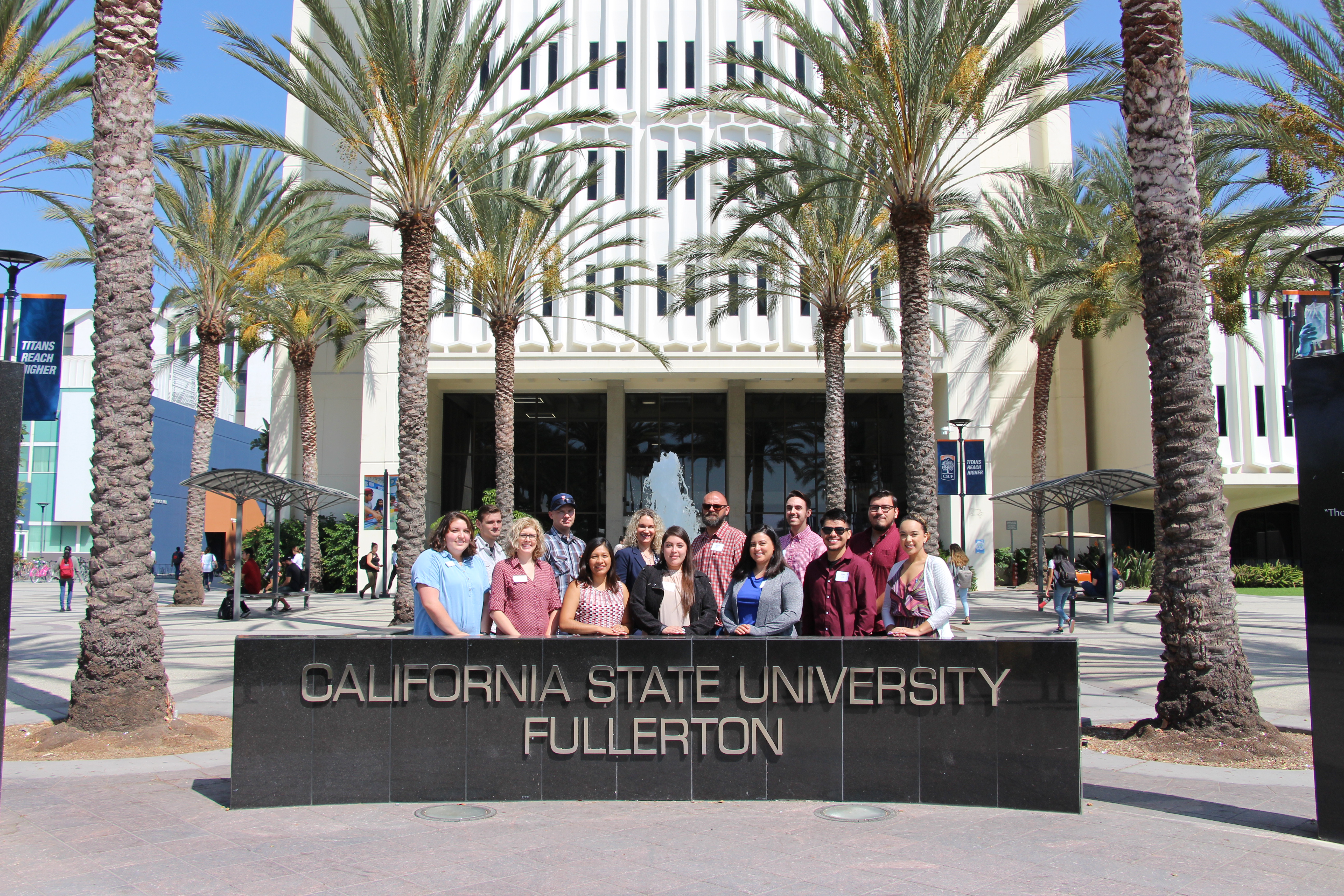 a group of people posing for a picture behind the CSUF sign 
