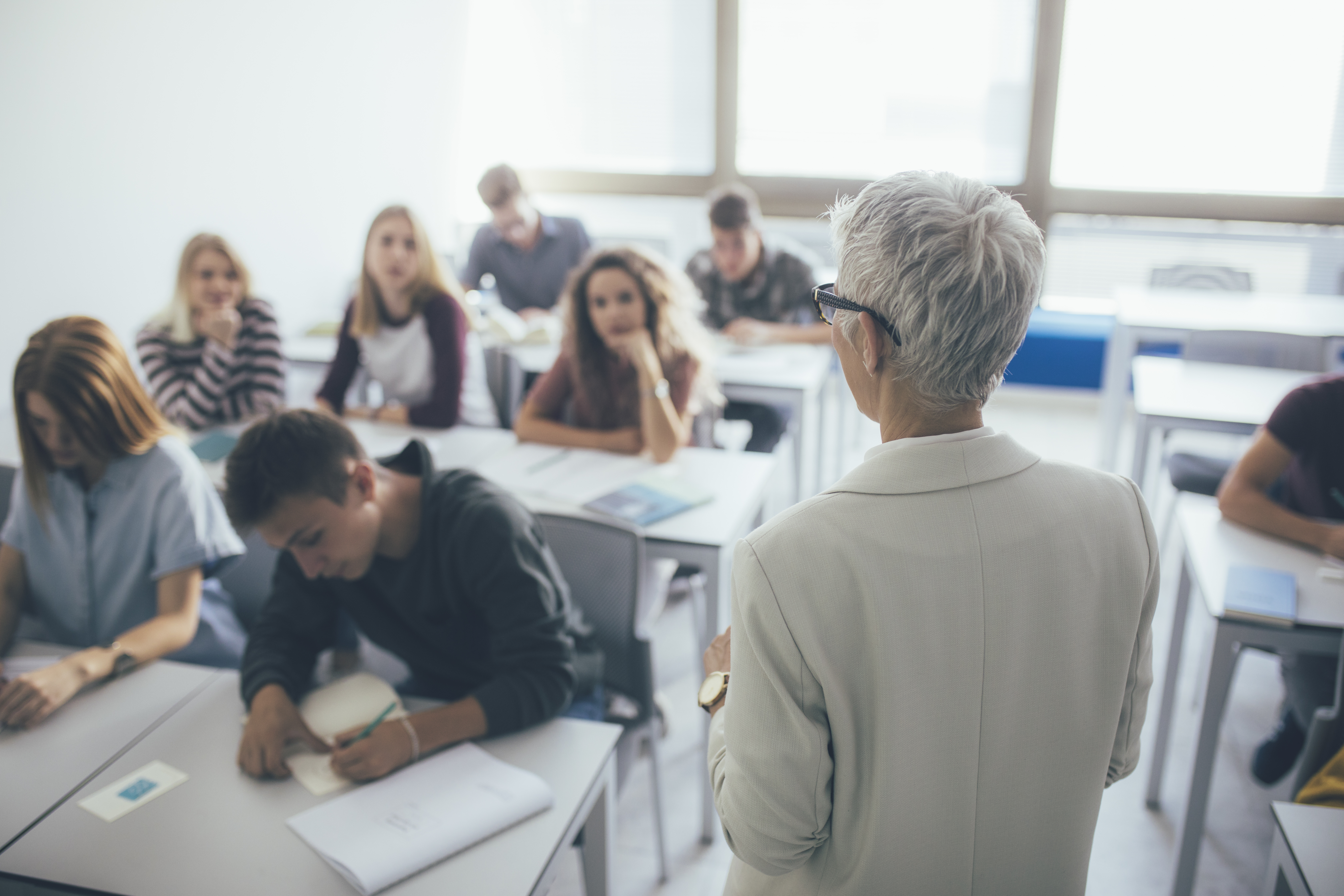 an older professor standing in front of a classroom full of students