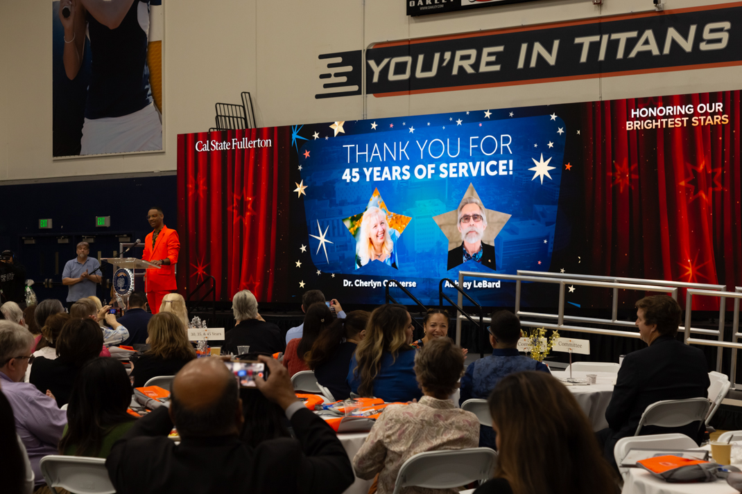 University recognition event with a speaker and a screen thanking individuals for 45 years of service.